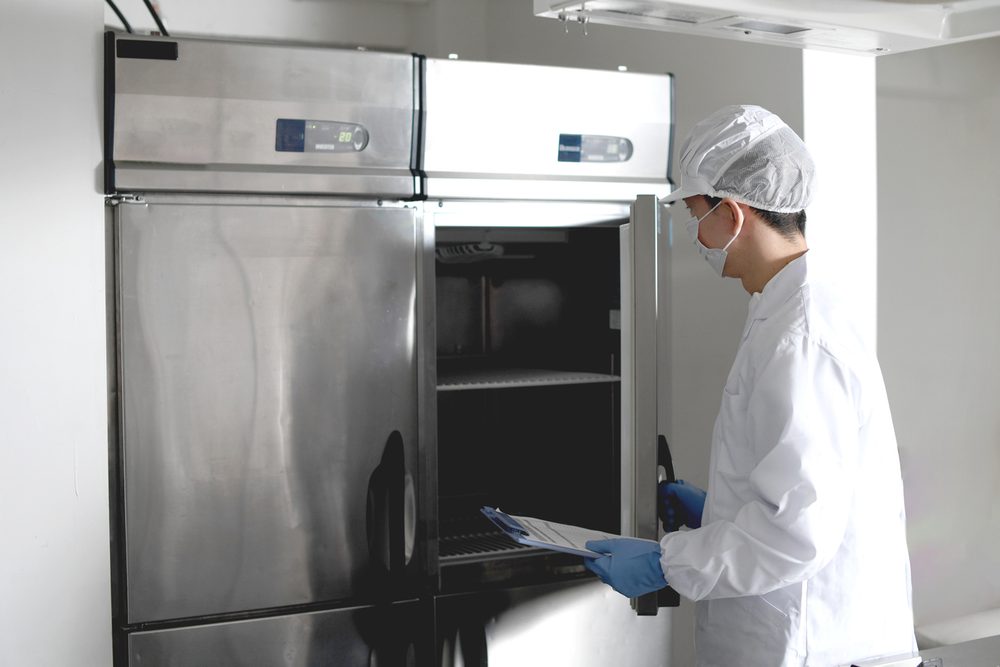 Technician inspecting a commercial reach-in refrigerator on Long Island