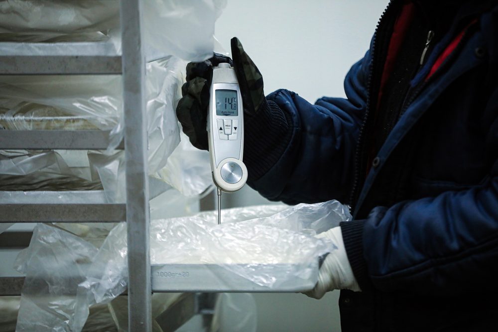 Technician checking the temperature inside a commercial walk-in freezer during an emergency call